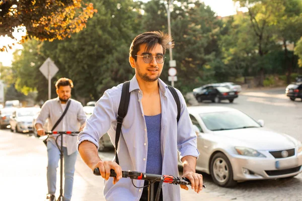 Щасливий студент їде на електричному скутері в місті — стокове фото