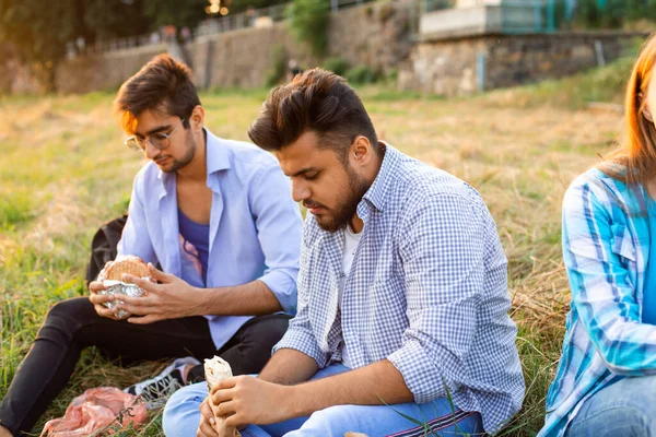 Os jovens estudantes multi-étnicos comendo fast food no campus — Fotografia de Stock