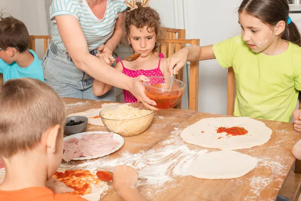 Los niños con un profesor están preparando pizza en la cocina. —  Fotos de Stock