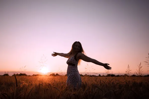 Friedliche Frau begrüßt die aufgehende Sonne auf dem Feld — Stockfoto