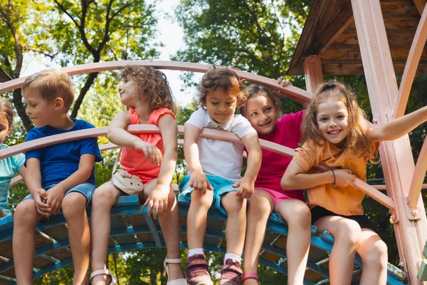 Los niños lindos están descansando en el patio de recreo en verano — Foto de Stock