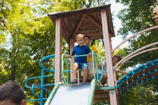 遊び場でスライドしようとしている幸せな小さな子供たち — ストック写真