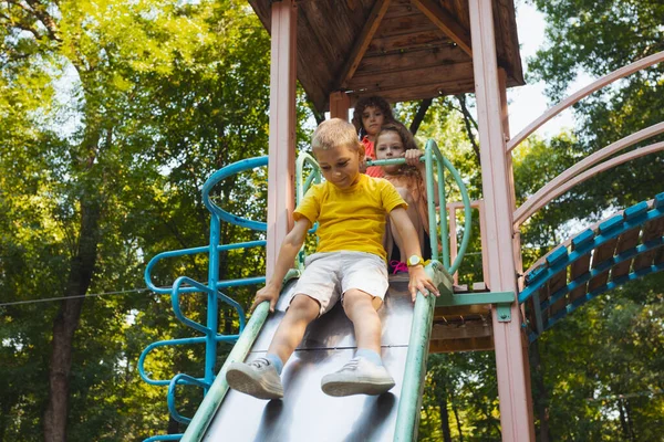 遊び場でスライドしようとしている幸せな小さな子供たち — ストック写真