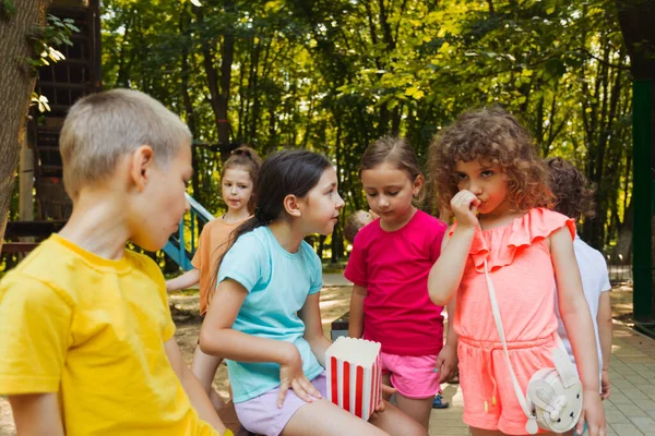 Les enfants mangent du pop-corn ensemble dans le parc. — Photo