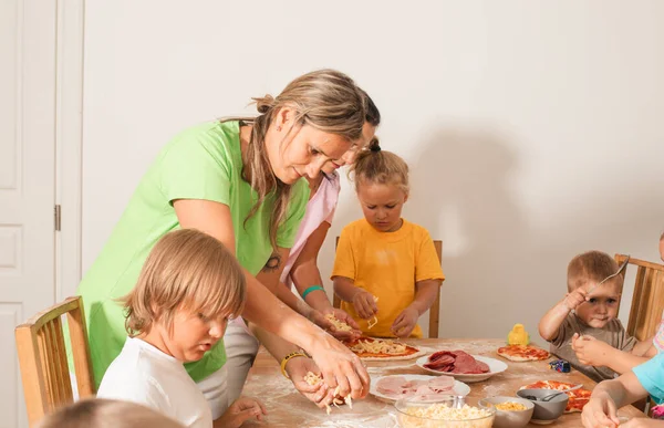Los educadores junto con los niños en edad preescolar hacen pizza —  Fotos de Stock
