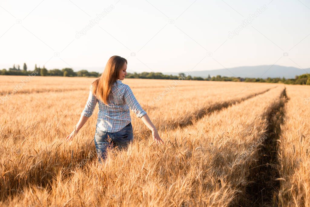 Charming woman enjoying moment, walking in grain field