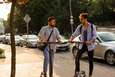 Şehirde elektrikli scooterları olan iki yetişkin öğrenci var.