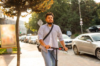 Genç adam elektrikli scooter kullanırken iyi bir ruh hali içinde.
