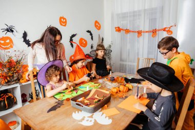 Öğretmen yaratıcı çocuklara kağıt yer imleri yapmaları için yardım ediyor