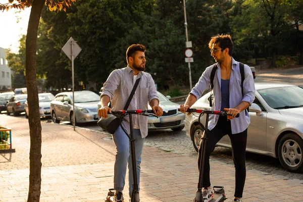 Двоє дорослих студентів стоять в місті з електричними скутерами — стокове фото
