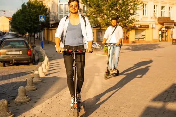 Dva dospělí studenti stojí ve městě s elektrickými skútry — Stock fotografie