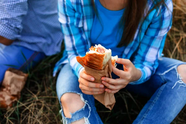 Kvinna äter en hamburgare utomhus sitter vid gräset — Stockfoto