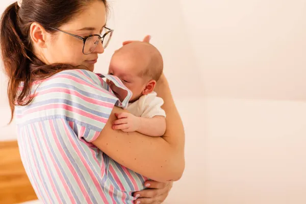 Young tired mother holding her newborn baby on her shoulder — Stock Photo, Image