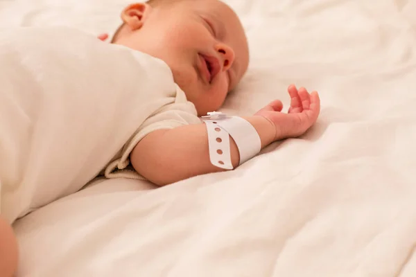 O bebê recém-nascido dorme na cama da maternidade — Fotografia de Stock