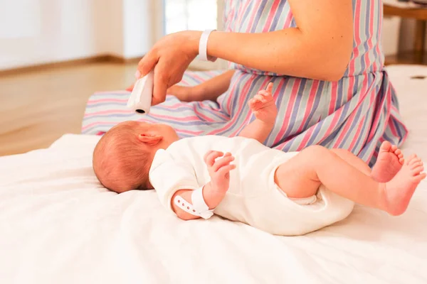 Η μητέρα μετρά τη θερμοκρασία του νεογέννητου μωρού στο κρεβάτι — Φωτογραφία Αρχείου