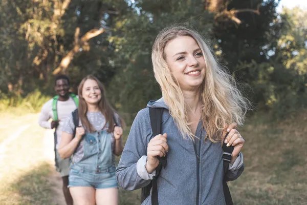 De glada unga vännerna vandrar i sommarskogen — Stockfoto