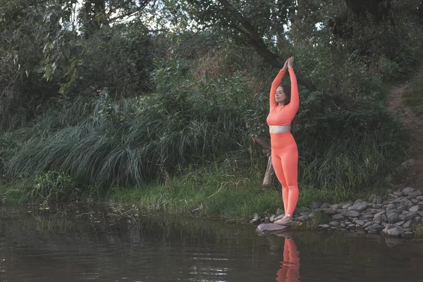 La joven con los ojos cerrados está meditando junto al río —  Fotos de Stock