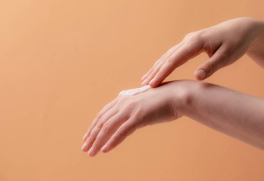 Genç kadın elleri krem ya da losyon sürüyor
