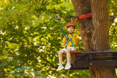 Sevimli anaokulu öğrencisi halatla kaymaya hazırlanıyor.