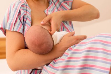 Anne yeni doğmuş bebeğini yatakta emziriyor.