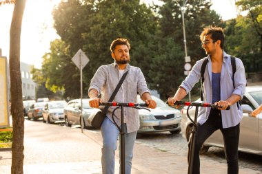 Şehirde elektrikli scooterları olan iki yetişkin öğrenci var.