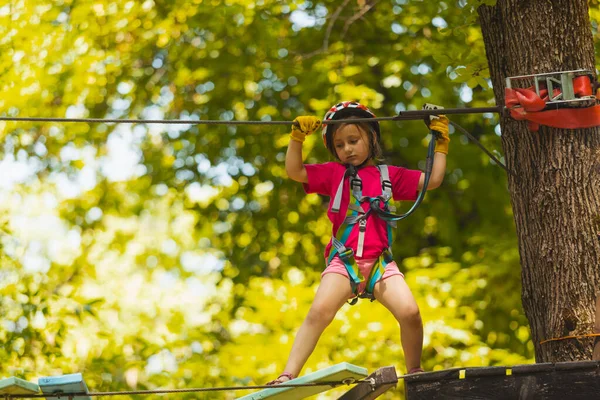 A koncentrált lány óvatosan legyőzi az akadályokat a kötélparkban. — Stock Fotó