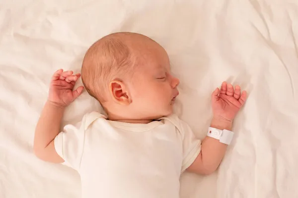 Yeni doğan bebek doğum hastanesindeki yatakta uyuyor. — Stok fotoğraf