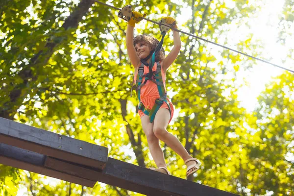 A koncentrált lány óvatosan legyőzi az akadályokat a kötélparkban. — Stock Fotó