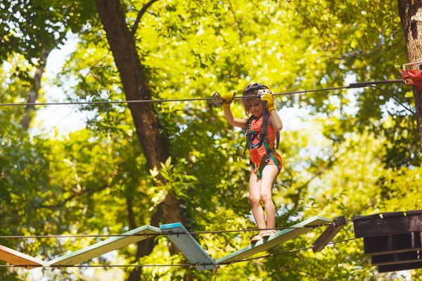 Het geconcentreerde meisje overwint voorzichtig obstakels in het touwenpark — Stockfoto