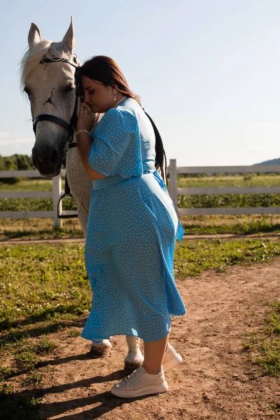 A mulher com cabelo encaracolado se agarra ao cavalo — Fotografia de Stock