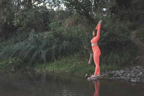 Die junge Frau mit geschlossenen Augen meditiert am Fluss — Stockfoto