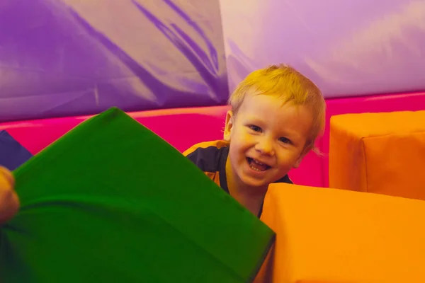 O menino bonito da criança está de pé entre cubos macios — Fotografia de Stock