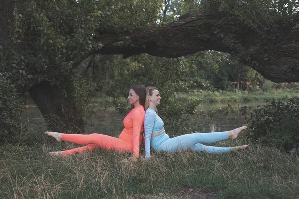 Zwei glückliche junge Freundinnen praktizieren Yoga im Freien — Stockfoto