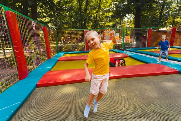 Το χαρούμενο παιδί έχει μια ωραία μέρα στο πάρκο με τα τραμπολίνα. — Φωτογραφία Αρχείου