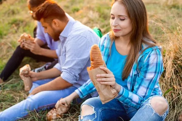 Den grupp unga olika människor som äter snabbmat på naturen — Stockfoto