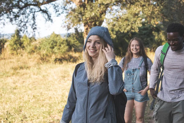 De glada unga vännerna vandrar i sommarskogen — Stockfoto