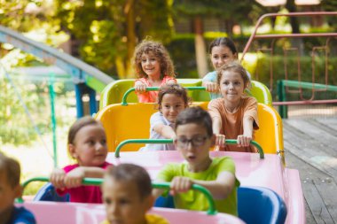 Lunaparktaki lunaparkta hız trenindeki mutlu çocuklar.