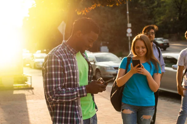 Los estudiantes multiétnicos con teléfonos inteligentes están navegando en Internet — Foto de Stock