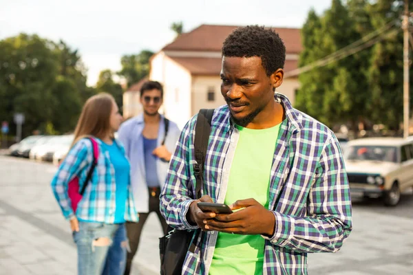 El joven estudiante africano utiliza la navegación en un smartphone — Foto de Stock