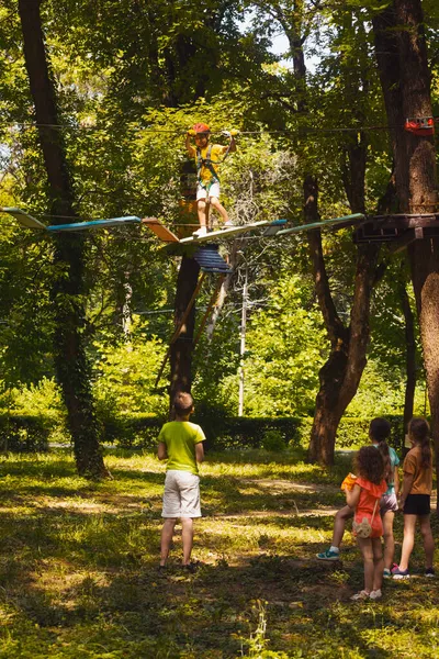 Los niños están mirando a su amigo en el parque de cuerdas. — Foto de Stock