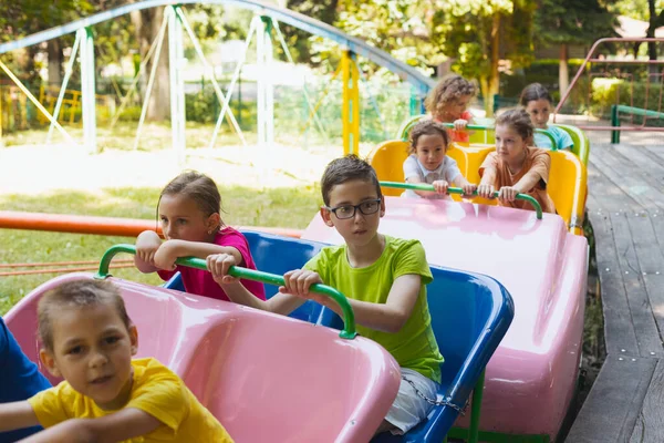 Los niños pequeños felices están descansando en el parque de atracciones — Foto de Stock