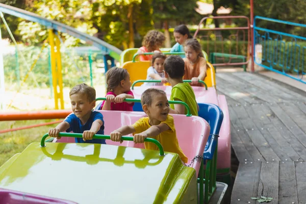 遊園地のジェットコースターの上の幸せな子供たち — ストック写真