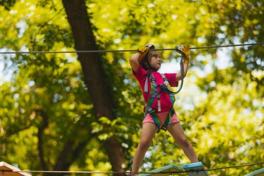 Yoğunlaşmış kız dikkatle halat parkındaki engelleri aşıyor.