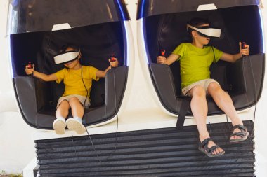 Küçük çocuklar oyunu dışarıda sanal gerçeklik gözlükleriyle oynuyorlar.