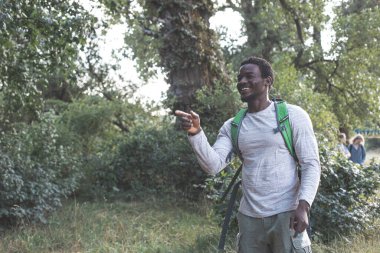 Sırt çantalı genç adam ormanda yürüyüş yapıyor.