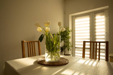 Bahar çiçekleri - ahşap masada cam vazoda beyaz laleler