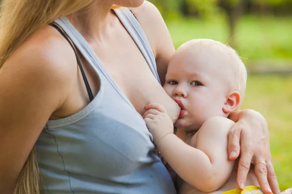 Madre che allatta il suo bambino seduto sull'erba — Foto Stock