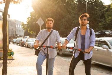 Şehirde elektrikli scooterları olan iki yetişkin öğrenci var.