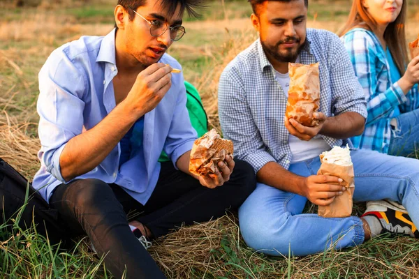Os jovens estudantes multi-étnicos comendo fast food no campus — Fotografia de Stock