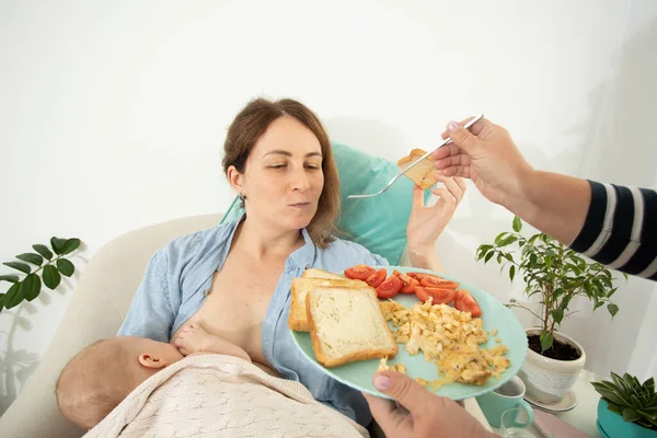 Apoio à maternidade, ajuda para comer para a jovem mãe — Fotografia de Stock